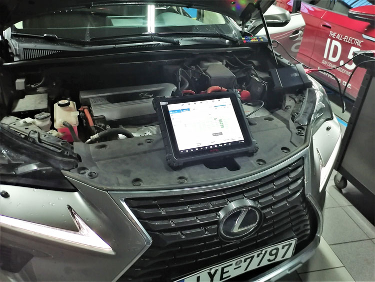 Ενα υβριδικό Lexus NX300h πριζωμένο στο διαγνωστικό οι συμμετέχοντες παρακολουθούν την τοπολογία εγκεφάλων δίπλα στο νεοαφιχθέν VW ID5
